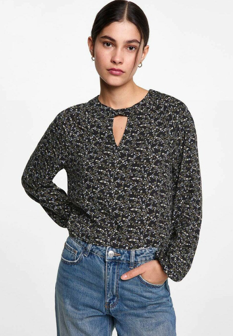 Zwarte blouse met lange mouwen, een bloemenpatroon, een sleutelgatsne neckline en een relaxte pasvorm, gecombineerd met hoog-was blauwe spijkerbroek.