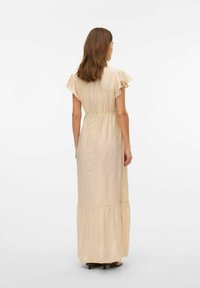 Maxi jurk in lichtbeige stof, met vlinder mouwen, elastische taille en een gelaagd rokje. Soepele textuur met een subtiele glans.