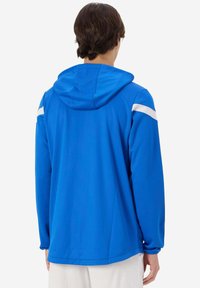 Felpa con cappuccio blu con strisce bianche di accento sulle spalle. Tessuto liscio e leggero con una vestibilità rilassata, che mette in evidenza un design semplice.