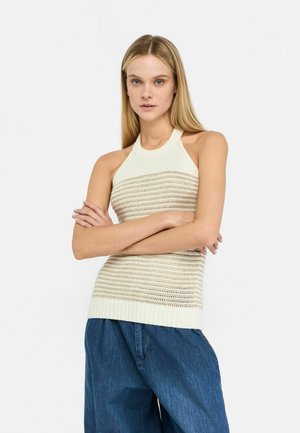 Haut en tricot crème avec un design à col halter et un motif rayé en openwork, associé à un pantalon en denim bleu ample. Texture lisse, finition douce.