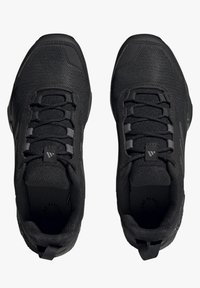 Par med svarta träningssneakers med nätöverdrag, vadderade kragar och snörning, sedda uppifrån mot vit bakgrund.