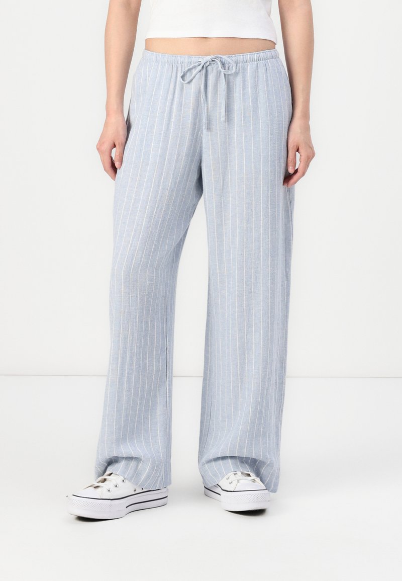 Pantalons larges bleu clair avec des rayures blanches verticales, confectionnés dans un tissu doux, dotés d'une taille élastique et d'un cordon de serrage.