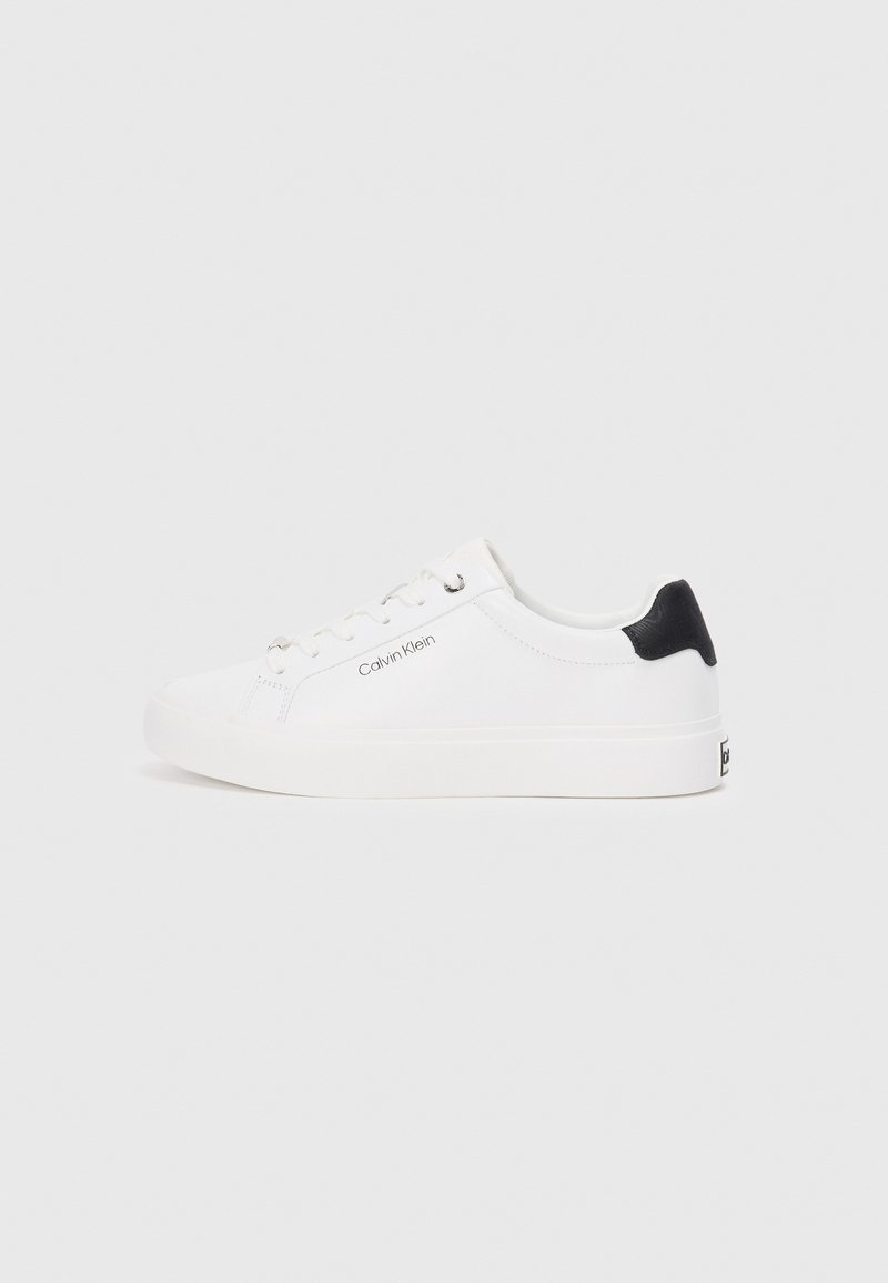 Bílé tenisky s černým koženým akcentem na patě. Mají hladký povrch, šněrování vpředu a decentní logo "Calvin Klein" na boku.