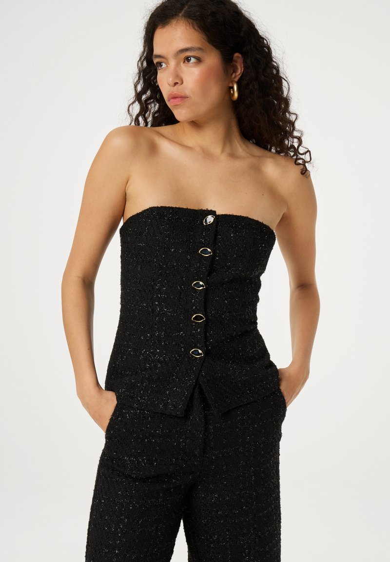 Zwarte strapless top van gestructureerde stof met een aansluitend ontwerp en goudkleurige knopen aan de voorkant.