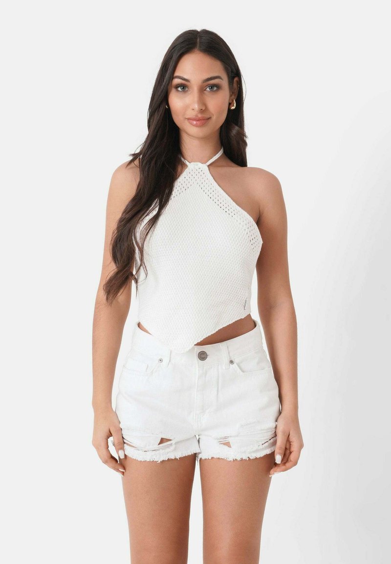 Witte gebreide haltertop met een ruitpatroon en een centrale knoop, gecombineerd met beschadigde witte denim shorts met rafelige randen.