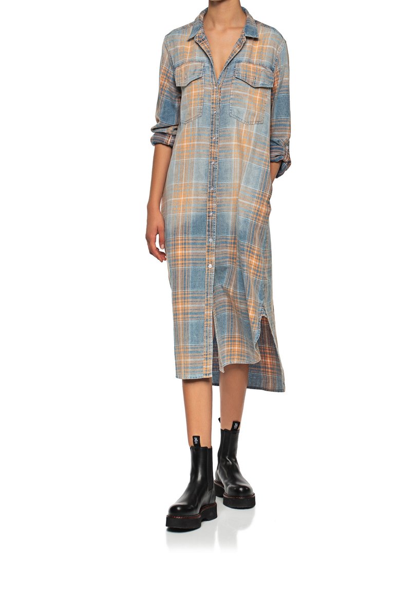 Lång rutig skjortklänning i blått och orange, med två bröstfickor, knappstängning framtill och sidofickor, kombinerad med svarta ankelstövlar.
