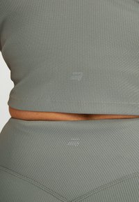 Gray ribbed activewear set featuring a cropped top and high-waisted leggings, with subtle branding and contrasting stitching details.