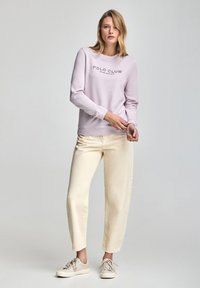 Sudadera de lavanda con logo "POLO CLUB", combinada con pantalones de pierna ancha color crema claro y zapatillas beige. Textura suave y corte relajado.