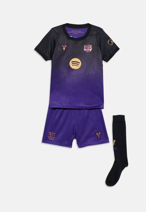 Sort og lilla FC Barcelona-fodboldsæt med gyldne logoer, inklusive trøje, shorts og én sort sok med et gyldent emblem.