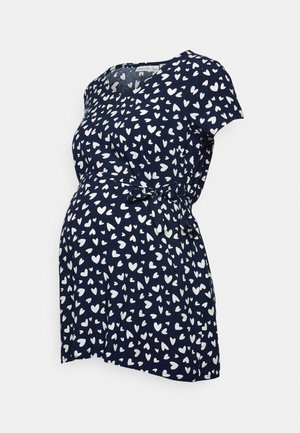 Vestido de maternidade azul-escuro com um padrão de corações brancos, mangas curtas e um laço na cintura para um ajuste definido na barriga.
