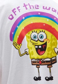 SpongeBob Schwammkopf lächelt mit einem Regenbogen, der über ihm spannt, und den Worten "Off the Wall" in lila Text darüber.