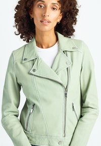 Miętowa skórzana kurtka motocyklowa z przednim zamkiem błyskawicznym, srebrnymi elementami i bocznymi kieszeniami. Posiada wycięty kołnierz i dopasowany fason.