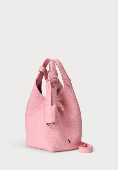 Roosa nahast käekott tekstureeritud viimistlusega, millel on üks käepide ja eemaldatav rihm. Ees väike logodetail.