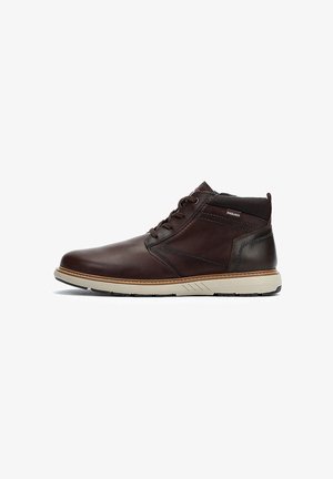 Bottines en cuir marron avec une finition lisse, semelle claire contrastante, accents cousus et un col rembourré pour le soutien.
