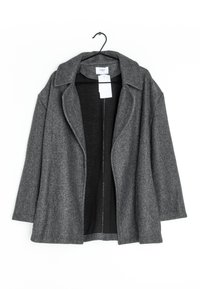Veste surdimensionnée en mélange de laine grise avec col cranté et ouverture frontale, présentant un intérieur noir et des détails de couture minimalistes.