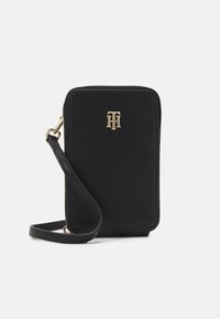 Musta rakenteinen käsilaukku, joka on tehty teksturoidusta materiaalista. Siinä on kultainen logokoriste ja irrotettava olkahihna helppoon kantamiseen.