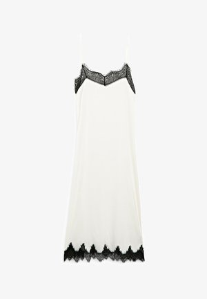 Biała sukienka na ramiączkach z delikatnymi czarnymi koronkowymi akcentami przy dekolcie i u dołu, charakteryzująca się cienkimi ramiączkami i gładką teksturą.