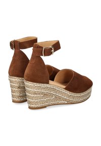 Brown suede espadrille wedges with an ankle strap, featuring a woven jute wedge heel and a smooth leather insole, designed with a rounded toe.
