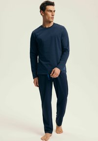 Granatowy zestaw piżamowy składający się z długiego, paskowanego topu z dekoltem w serek oraz luźnych spodni z zaszewkami w talii, wykonany z miękkiego materiału.