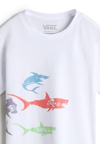 Weißes Baumwoll-T-Shirt mit bunten Haifischgrafiken in Blau, Rot, Lila und Grün. Klassische Passform mit rundem Ausschnitt und kurzen Ärmeln.
