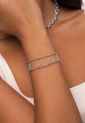 Bracciale in argento con maglie rettangolari e perle di turchese, creando un motivo alternato. Texture liscia con un design delicato.