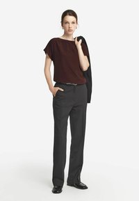 Bordeaux kortärmad blus, hög halsringning, ihopparad med skräddarsydda svarta byxor, slät textur, minimalistisk design, håller en svart kavaj.