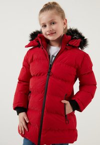 Rød puffjakke med lynlås foran, faux fur kravetrim og ribbede manchetter. Materialet har en glansfuld overflade med horisontale syninger.