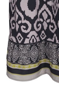 Svart och grått mönstrat tyg med intrikata vita blomster- och geometriska mönster samt en tunn guldkant nära kanten.