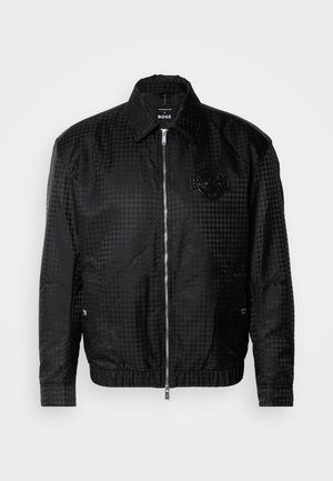Black check-patterned jacket made of smooth fabric, featuring a zip front, collar, elastic hem, and embossed logo detail on the chest.