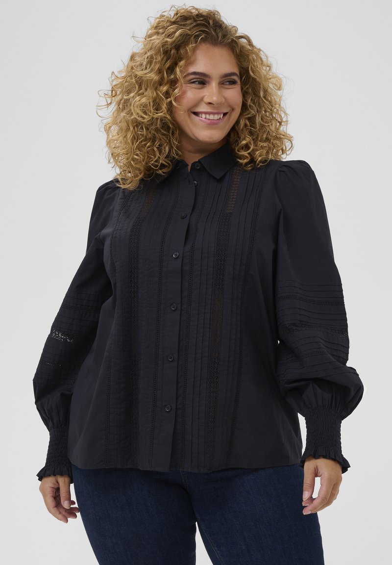 Camisa negra de botones con rayas texturizadas y detalles de encaje, que presenta mangas abullonadas y puños fruncidos. Tela suave con un ajuste entallado.