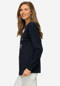 Granatowa koszulka z długim rękawem o luźnym kroju, z grafiką na przodzie i miękkiego, oddychającego materiału bawełnianego.