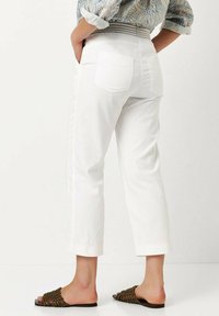 Witte cropped broek met twee achterzakken, gemaakt van denim. Soepele textuur, afgewerkte zoom, gecombineerd met bruin geweven slip-ons.