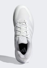 Biela športová obuv s textúrovaným sieťovinovým zvrškom, šnúrkami a tromi pruhmi na boku. Má vycpanú podrážku a polstrovaný golier.