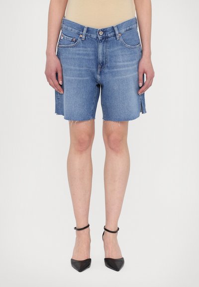 Denim shorts in light blue with frayed hems, five-pocket design, and a high-rise waist. Paired with black pointed heels.