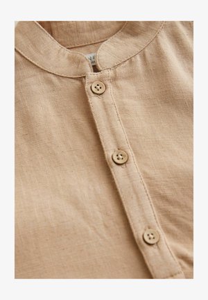 Top in lino marrone chiaro con colletto arrotondato, patta con quattro bottoni e una lieve texture. Design semplice e classico.