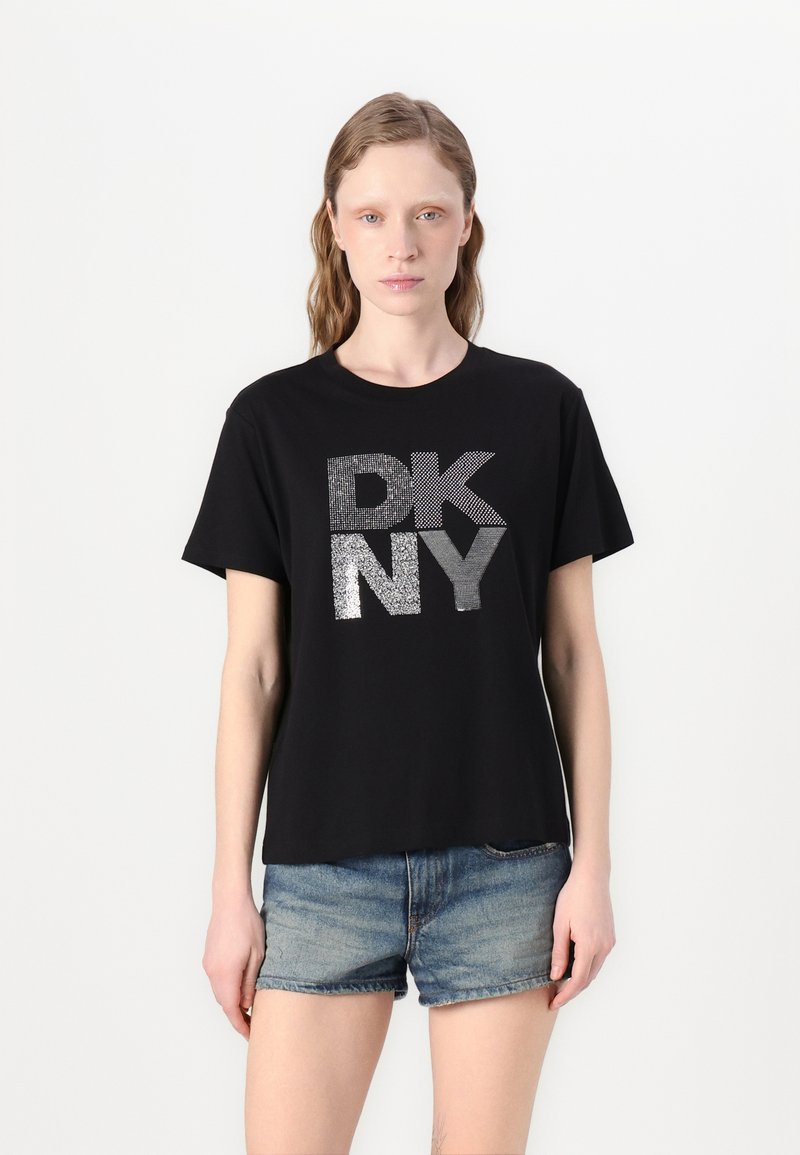 Juodas trumpas rankovėmis marškinėliai su sidabriniu blizgučio grafiku "DK NY" priekyje. Pagaminti iš minkštos medvilnės, jie turi laisvą siluetą.
