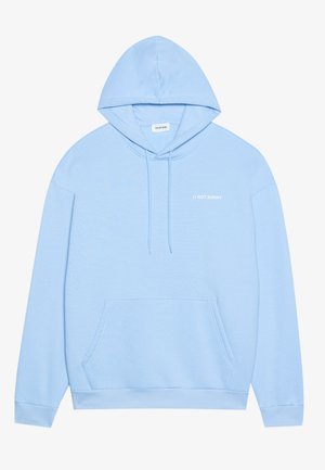 Lichtblauwe hoodie van zachte stof, met een kangoeroezak en een capuchon met trekkoord. Tekst "// NOT SORRY" in het wit gedrukt op de voorkant.