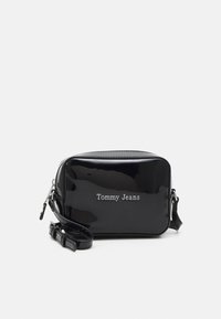 Borsa a tracolla in ecopelle nera lucida con logo, forma rettangolare, chiusura con zip e tracolla regolabile. Texture liscia con finitura lucida.