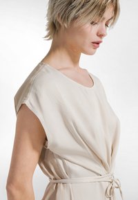 Beige, let kjole med løs pasform, rund halsudskæring og korte ærmer, med snøre i taljen for justerbar pasform.