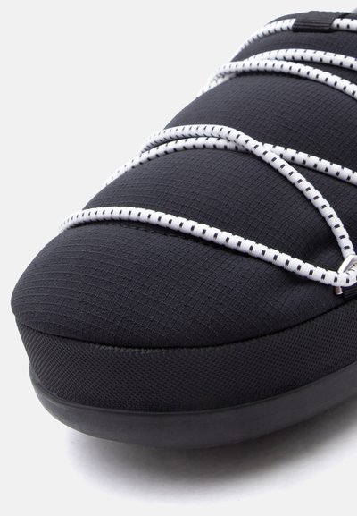 Μαύρο δάχτυλο αθλητικού παπουτσιού με υφασμάτινη επάνω επιφάνεια με υφή και λευκά ελαστικά κορδόνια με μαύρο πουά μοτίβο, τοποθετημένο σε λευκό φόντο.