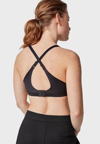 Soutien-gorge de sport noir avec un design dos nageur, bretelles réglables et fermeture à pression, mettant en valeur un tissu lisse et un style minimaliste.