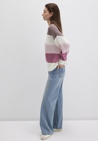 Knitted sweater with horizontal stripes in shades of mauve and cream, paired with high-waisted light blue wide-leg jeans.