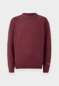 Suéter de punto burdeos con cuello redondo acanalado y puños. Textura suave, con un pequeño detalle bordado en la manga.