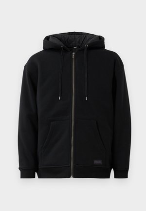 Black zip-up hoodie made of fleece, featuring a drawstring hood, front pockets, and ribbed cuffs. The interior has a quilted texture.