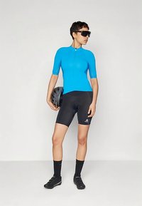 Maillot de cyclisme bleu à manches courtes, cuissard noir, chaussettes noires et chaussures de cyclisme ; tenant un casque noir ; design minimaliste.