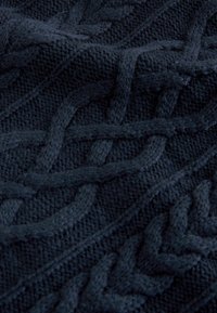 Mørk navy strikket stof med intrikate kabelmønstre, der viser tekstur og dybde i close-up visning.