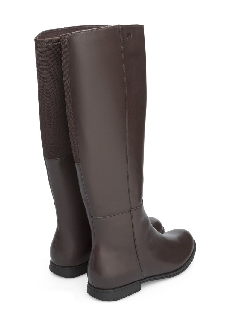 Stivali alti in pelle marrone con una superficie liscia, dotati di un pannello in maglia sul retro e una suola in gomma bassa e piatta.
