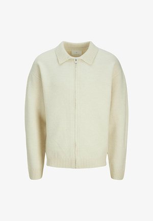 Bežani pleteni pulover s patentnim zatvaračem na prednjem dijelu, ovratnikom te rebrastim manžetama i rubom. Ima mekanu teksturu i opušteni kroj.