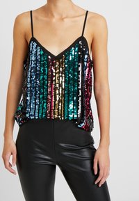 Paljettopp med svarta band, med vertikala ränder i teal, blått, guld och rosa. Lös passform med V-ringning och glänsande textur.
