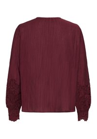 Bordeaux bluse med lange, strukturerede ærmer med intrikate blonder. Blødt, letvægts stof med en afslappet pasform.